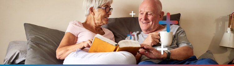 Couple portraying a TALZENNA® (talazoparib) + XTANDI® (enzalutamide) patient and caregiver in bed reviewing ways to help manage certain side effects